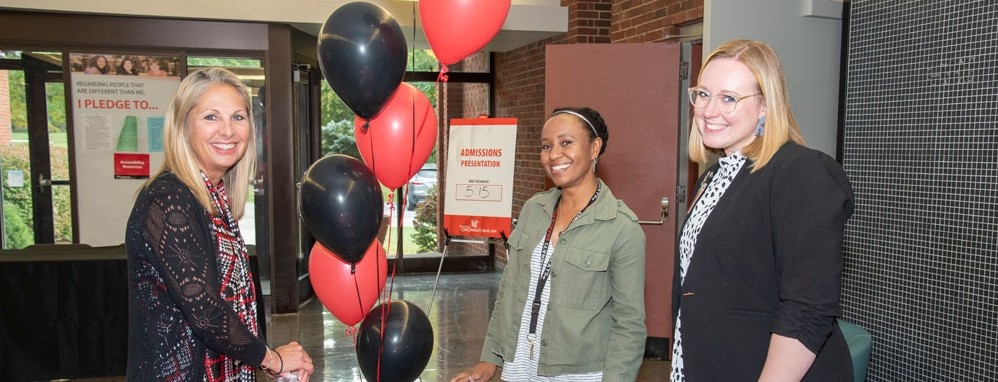 three UC Blue Ash staff members smiling during an event