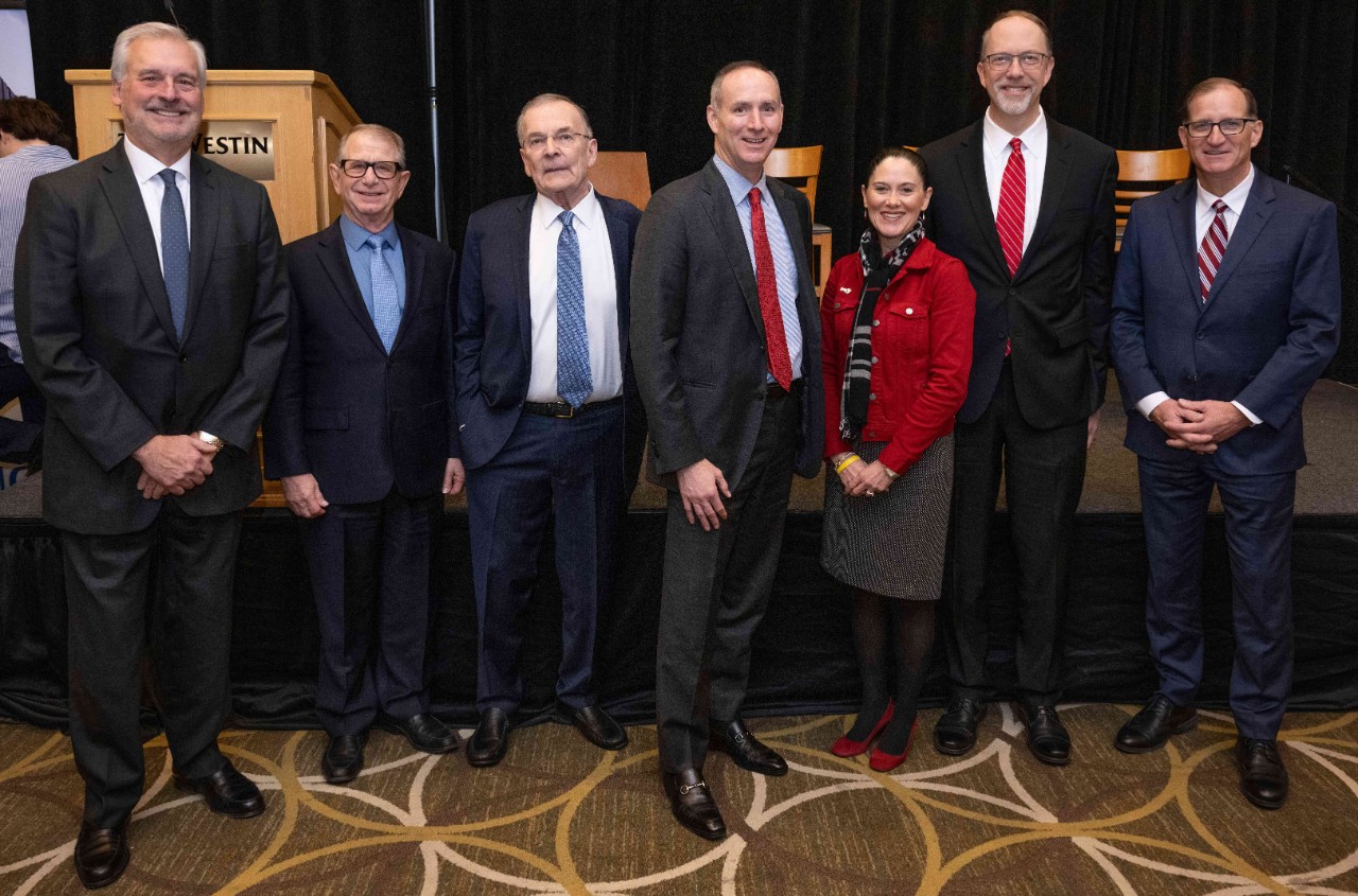 Real Estate Center employees with PNC employees at the Economic Outlook, all in professional dress standing in front of a stage
