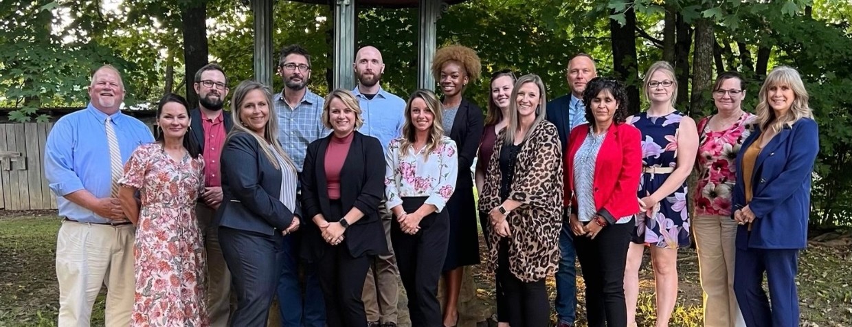 Community leaders standing and smiling outside in front of a small gazebo