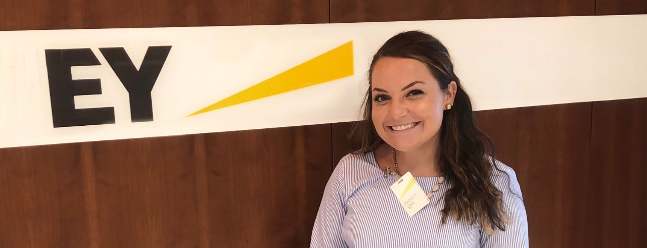 Abby Bame in front of an Ernst & Young sign 