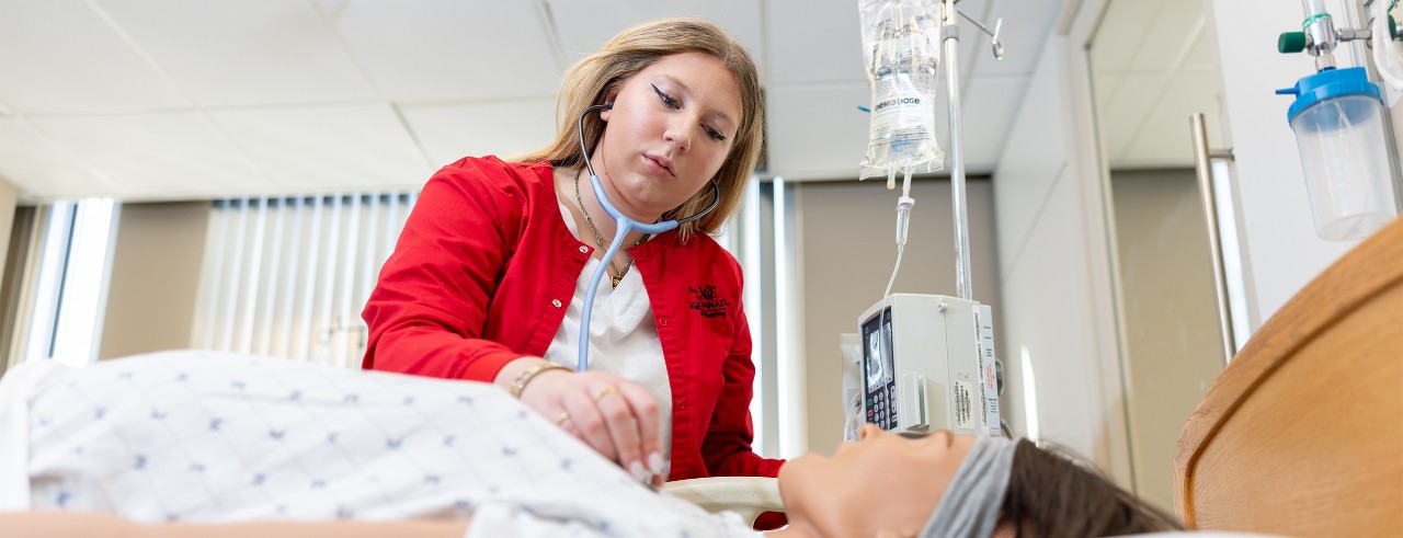 Elisse Martin is shown standing over a simulated patient laying in a bed