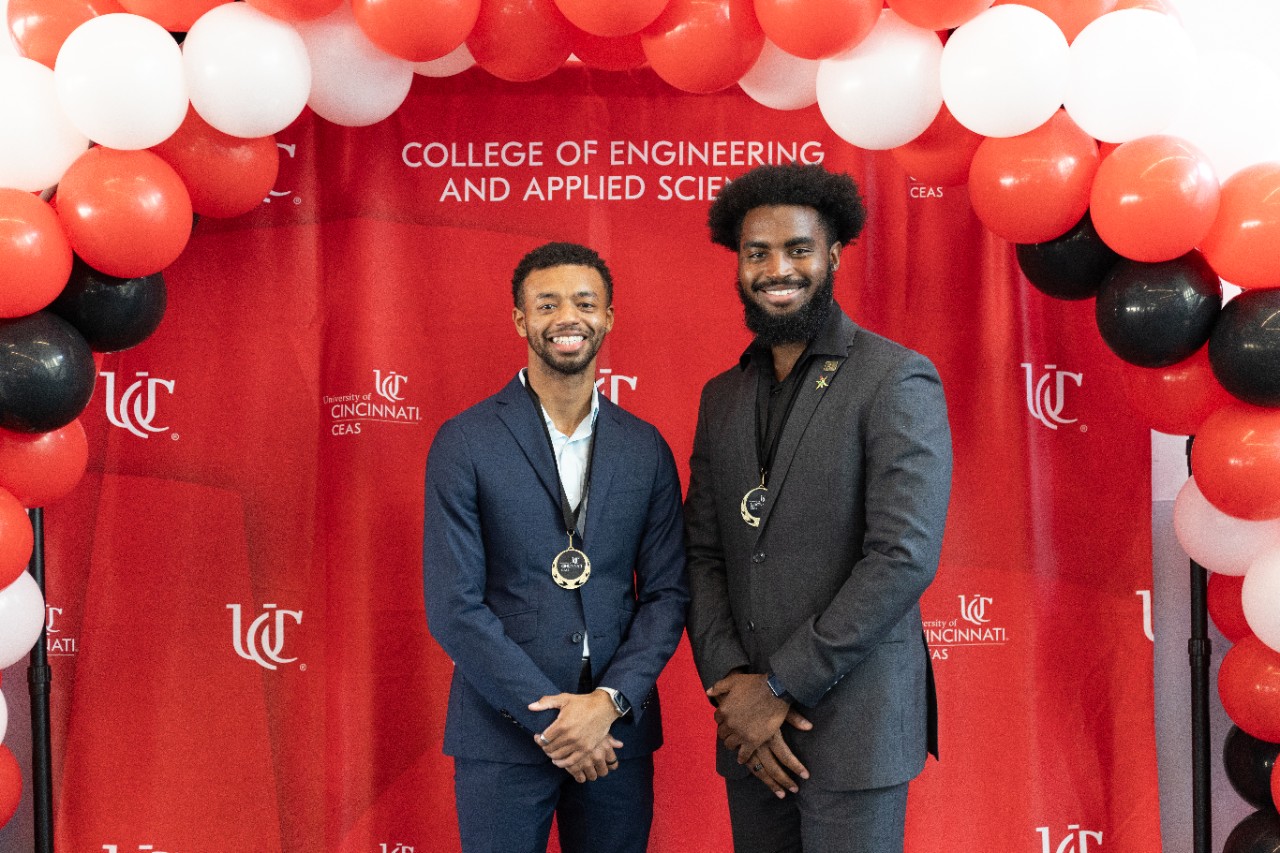 Michael Hunter (left) and Daylan Dallas (right) in front of a red UC CEAS backdrop. 