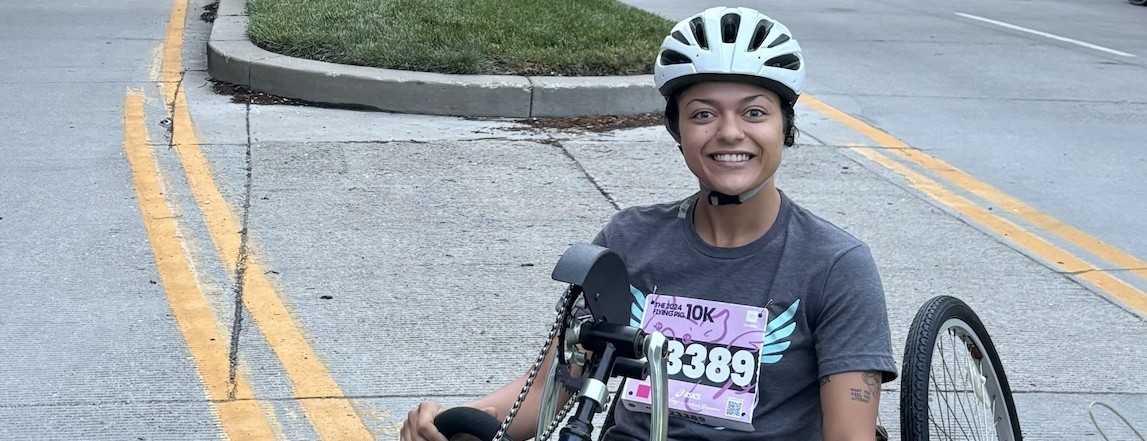 Mikiahya Greene wears a helmet and smiles while sitting in a racing wheelchair