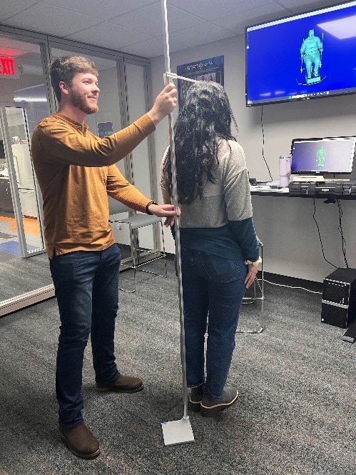 Aidan Saylor, testing his creation by measuring a co-worker, the newly minted base standing firm.