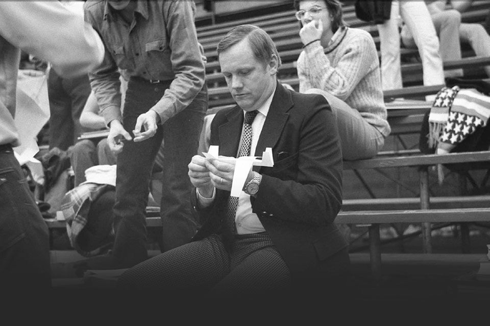 Neil Armstrong sits in bleachers with his students making paper airplanes. 