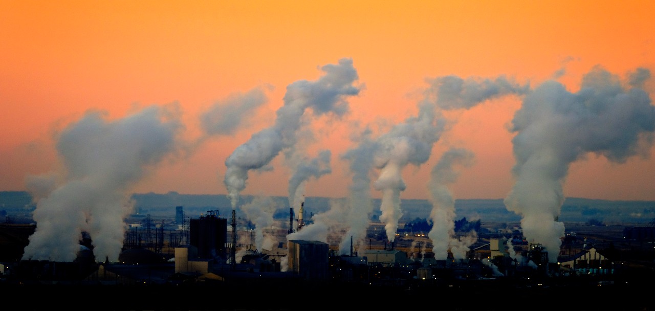 image of industrial complex with several smoke stacks polluting the atmosphere