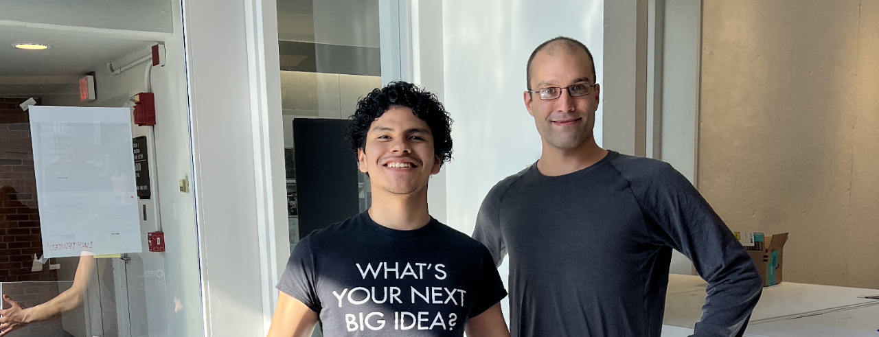 Caleb Loayza and Guy Mueller hold a giant check after their competition win. 
