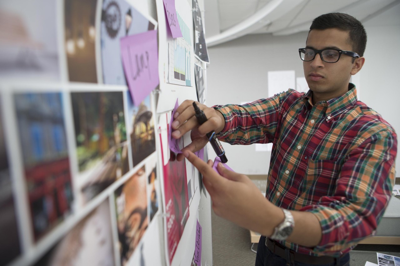Man with glasses organizes photos on a board