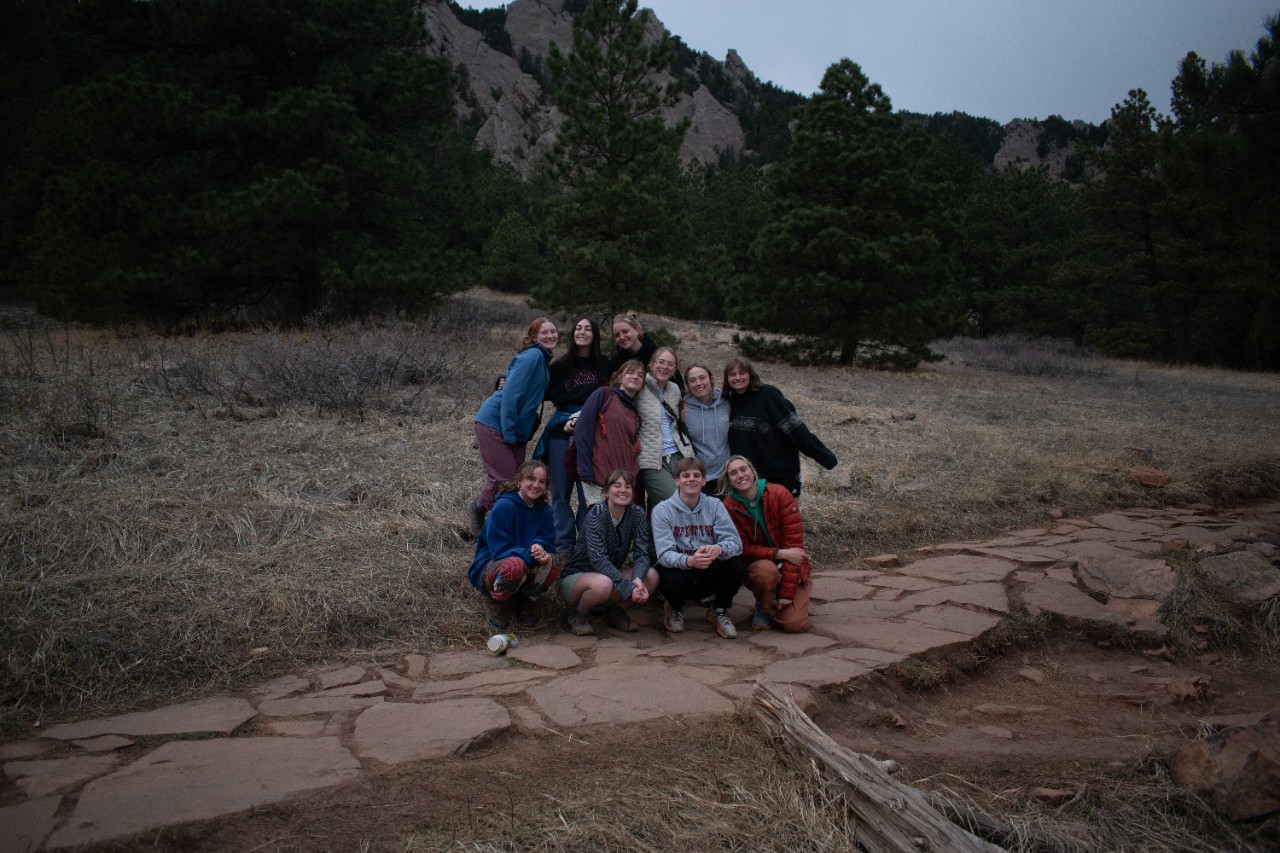 A group of UC students huddled in front of a mountain range 