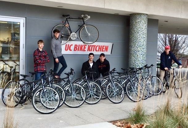 Several students stand with a dozen bicycles in front of UC's Bike Kitchen.
