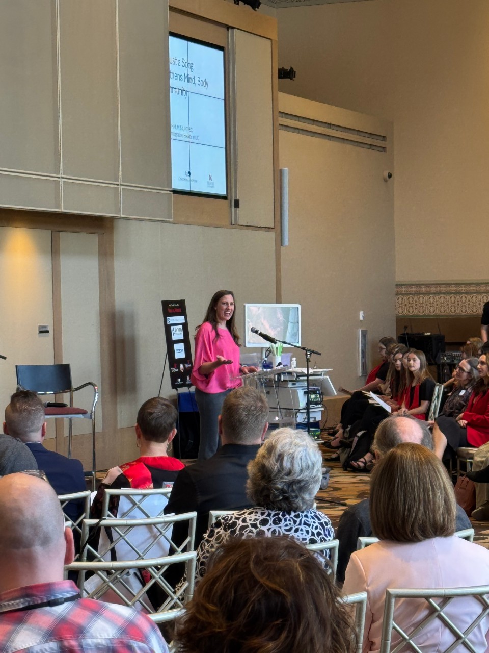 a presenter stands on a stage in front of an audience