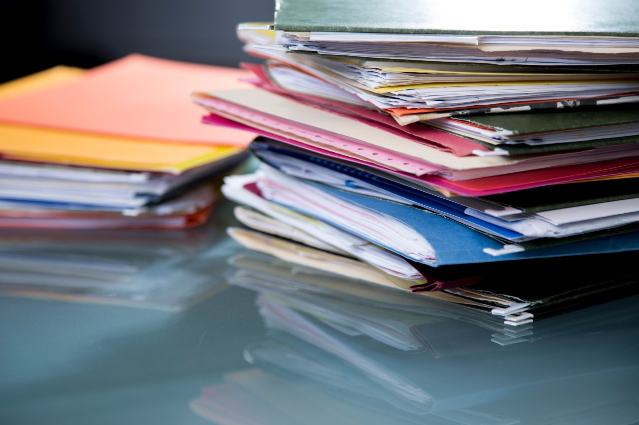 several folders filled with papers sit on a desk