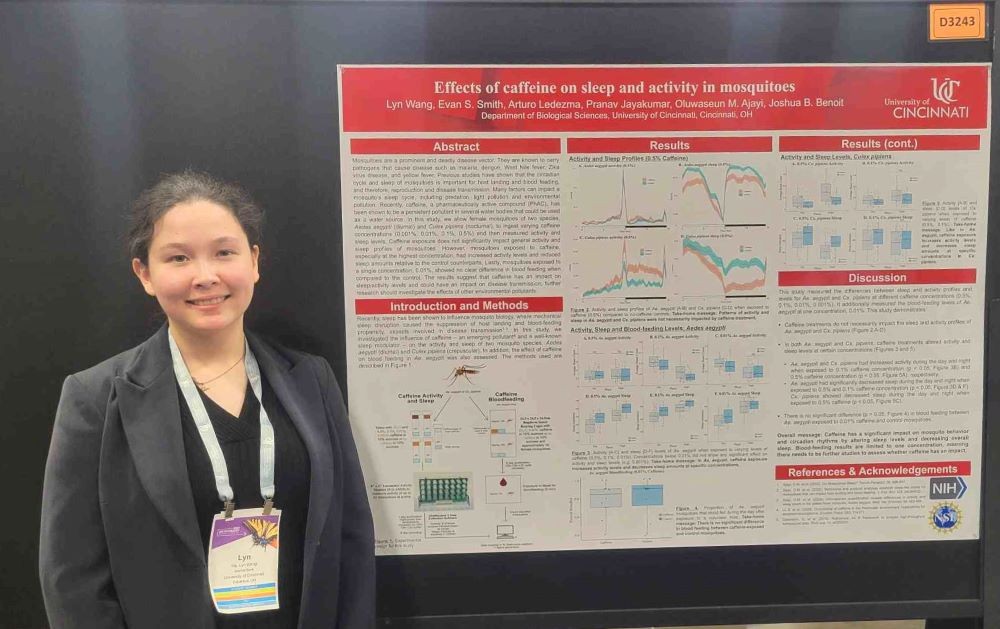 young woman poses next to a research poster