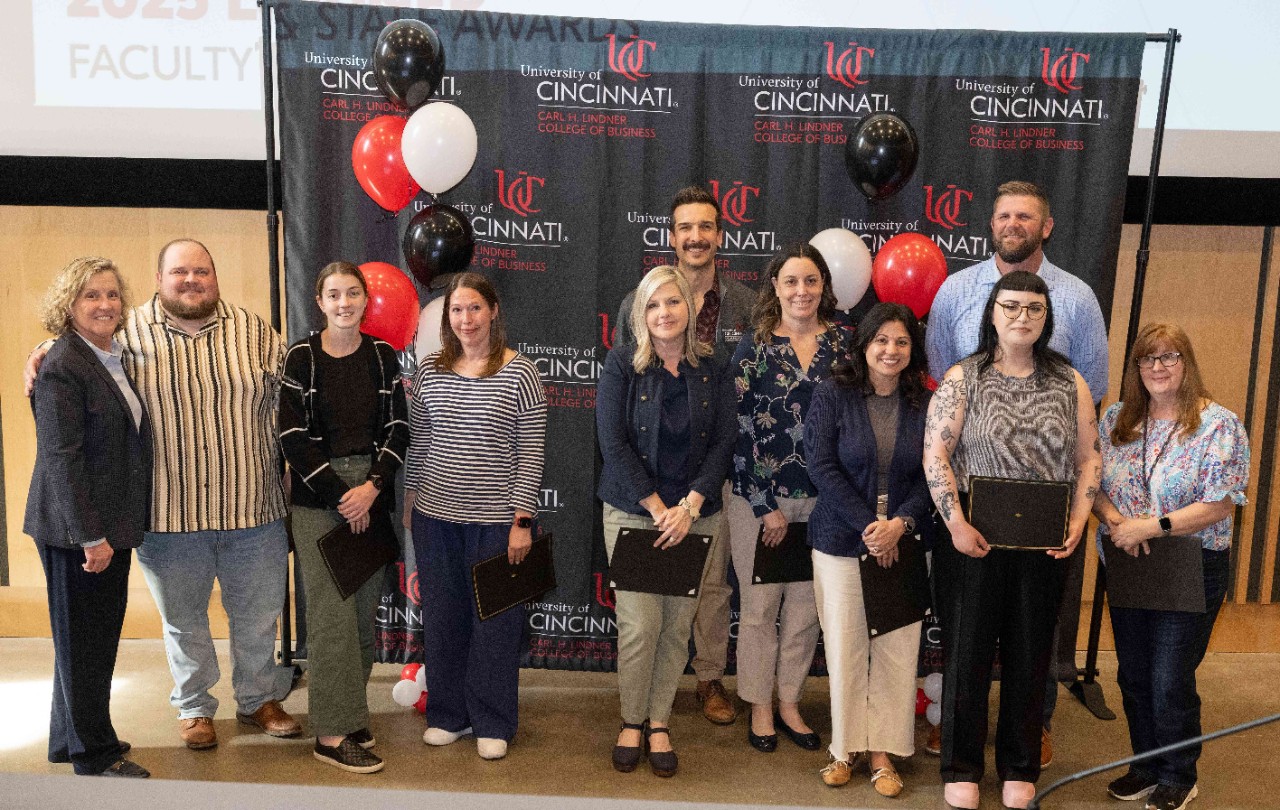 Lindner staff members pose in front of a black banner with balloons.