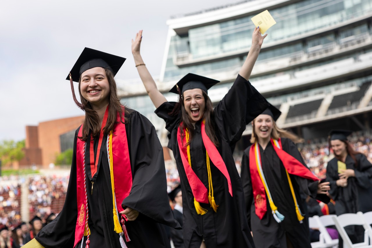 Graduates celebrate on the field at Nippert Stadium.
