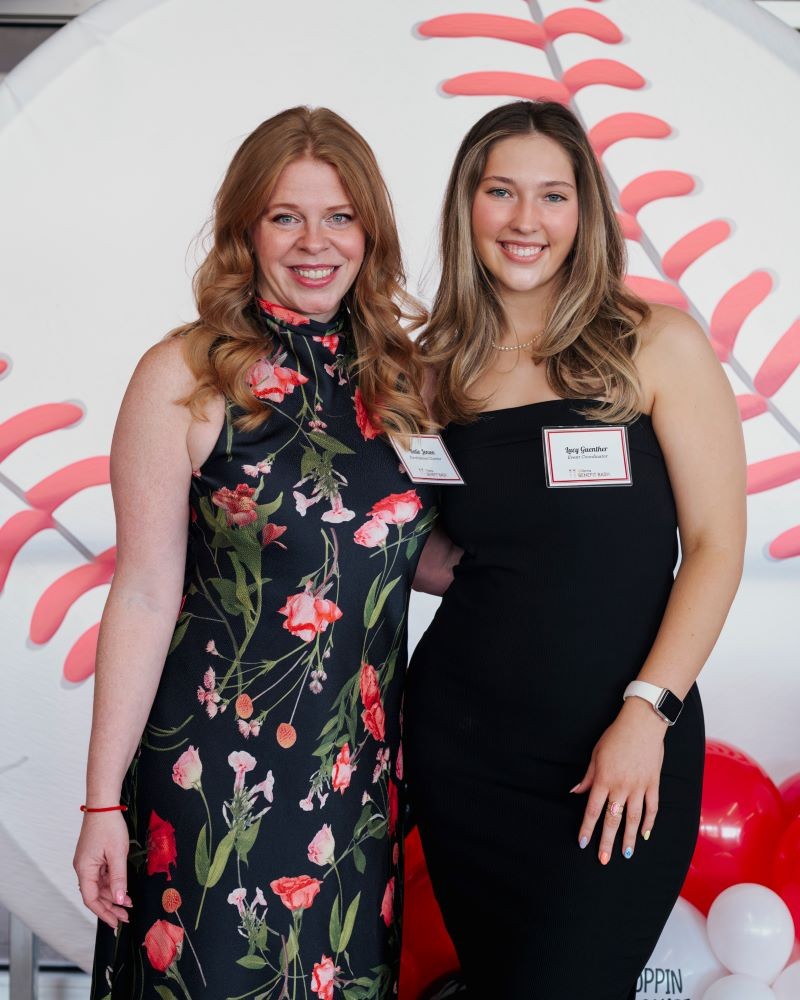 two women in dresses pose for the camera