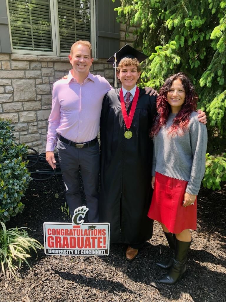 Caden Elrod in cap and gown with parents at their Cincinnati home
