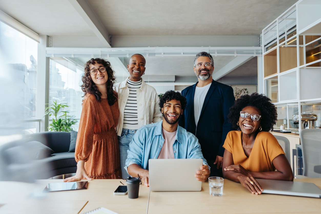 Young professionals meet around table, looking happy