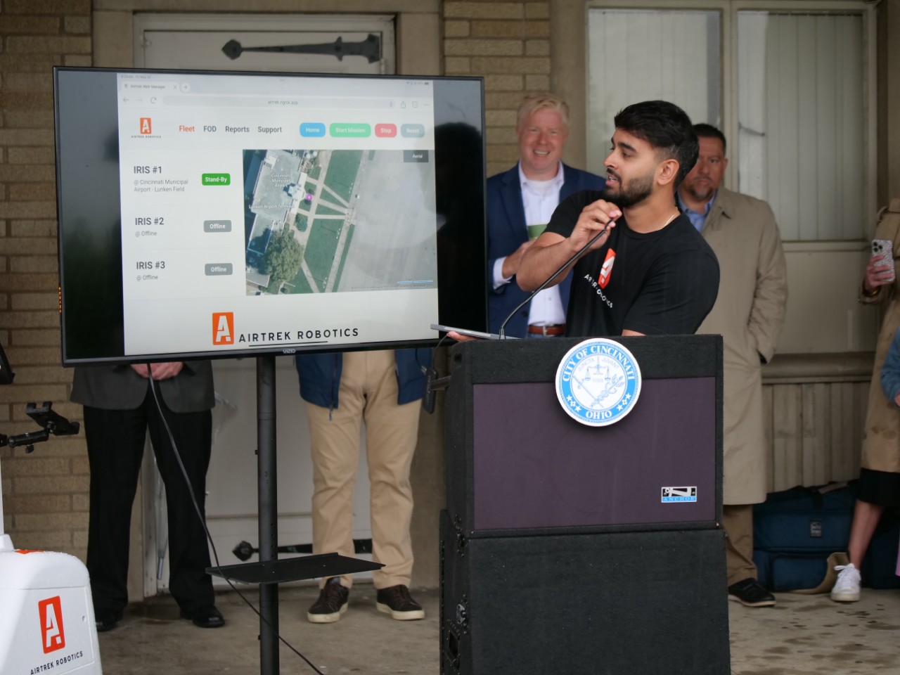 Airtrek cofounder and chief technology officer, Huzefa Dossaji, stands in front of a monitor to explain the robot's technology.