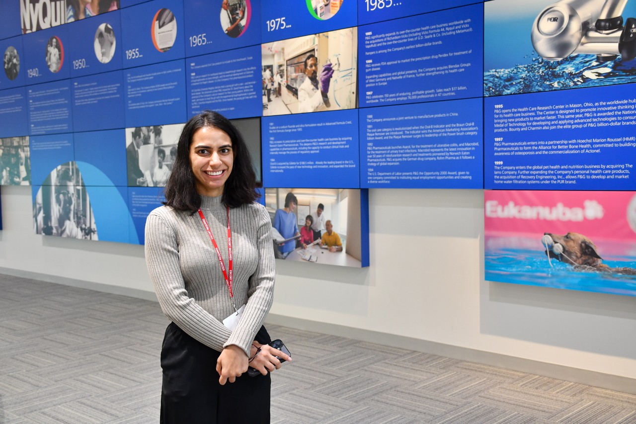 Manisha Sheokand stands in front of a mural outlining P&G's milestones.