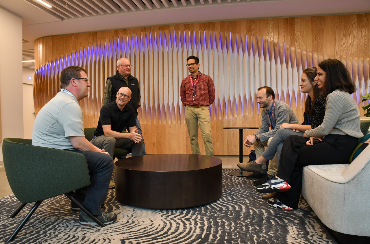 A group of people huddle around a table in a lounge at P&G.