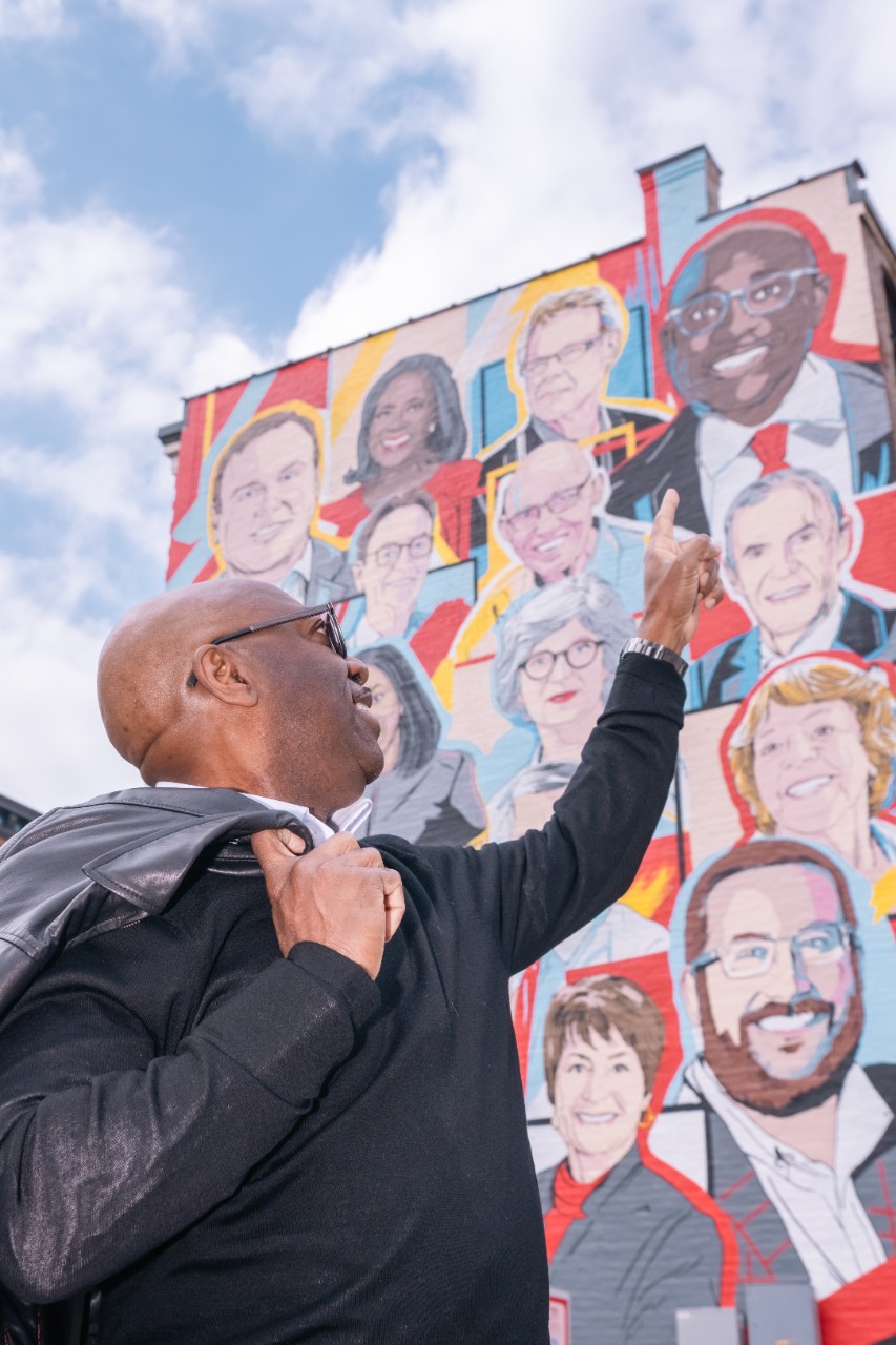 Darrell points to his portrait atop the UC Alumni Celebration mural