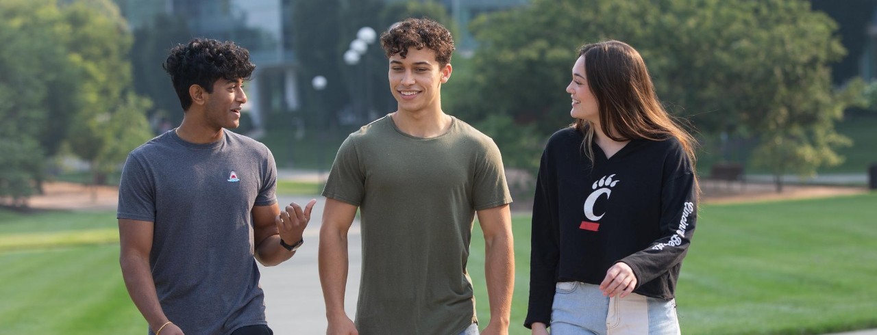 Three friends in college walking on UC's campus