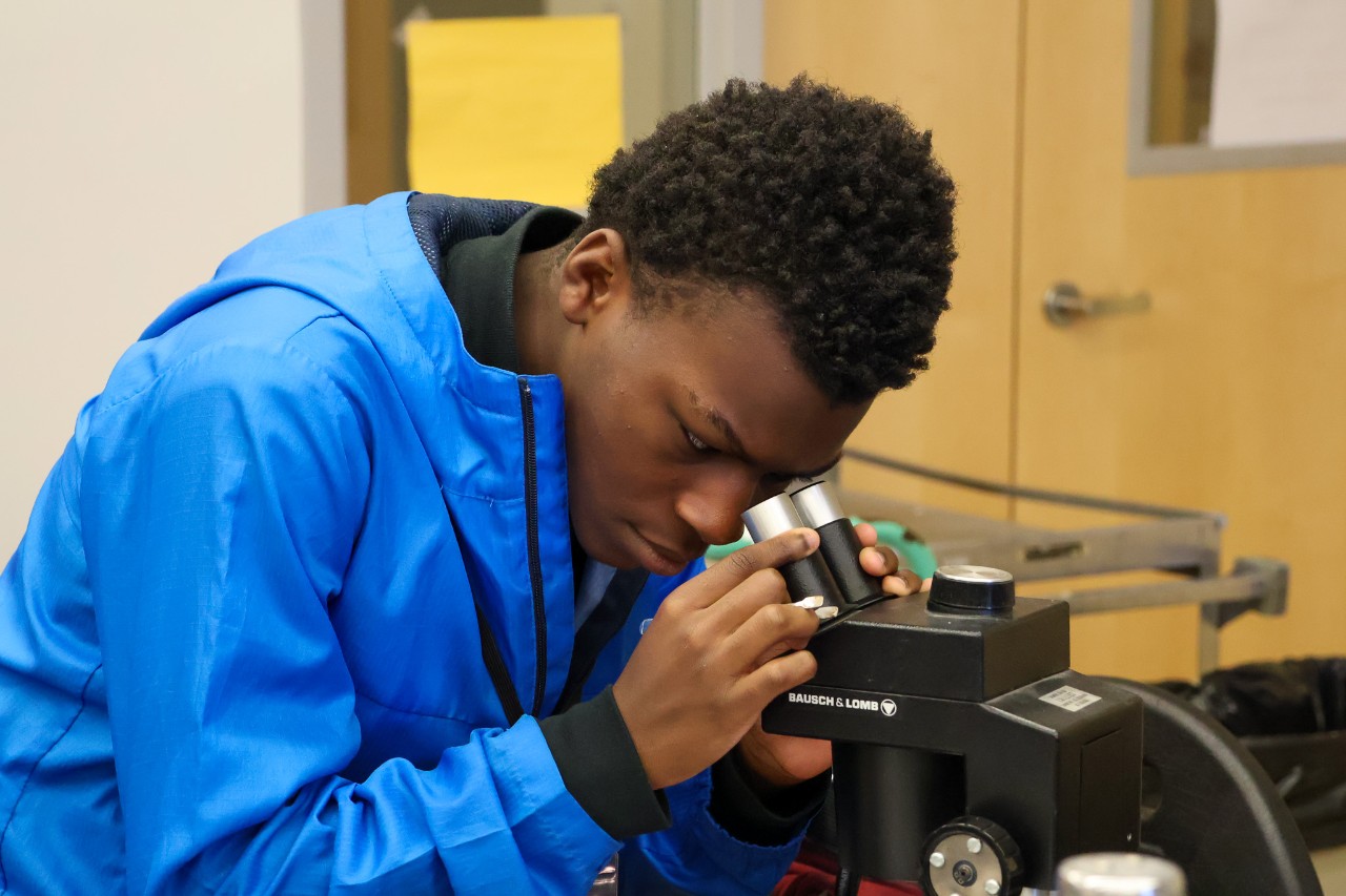 Hughes high school ninth-grader peers through a microscope during Biology Day