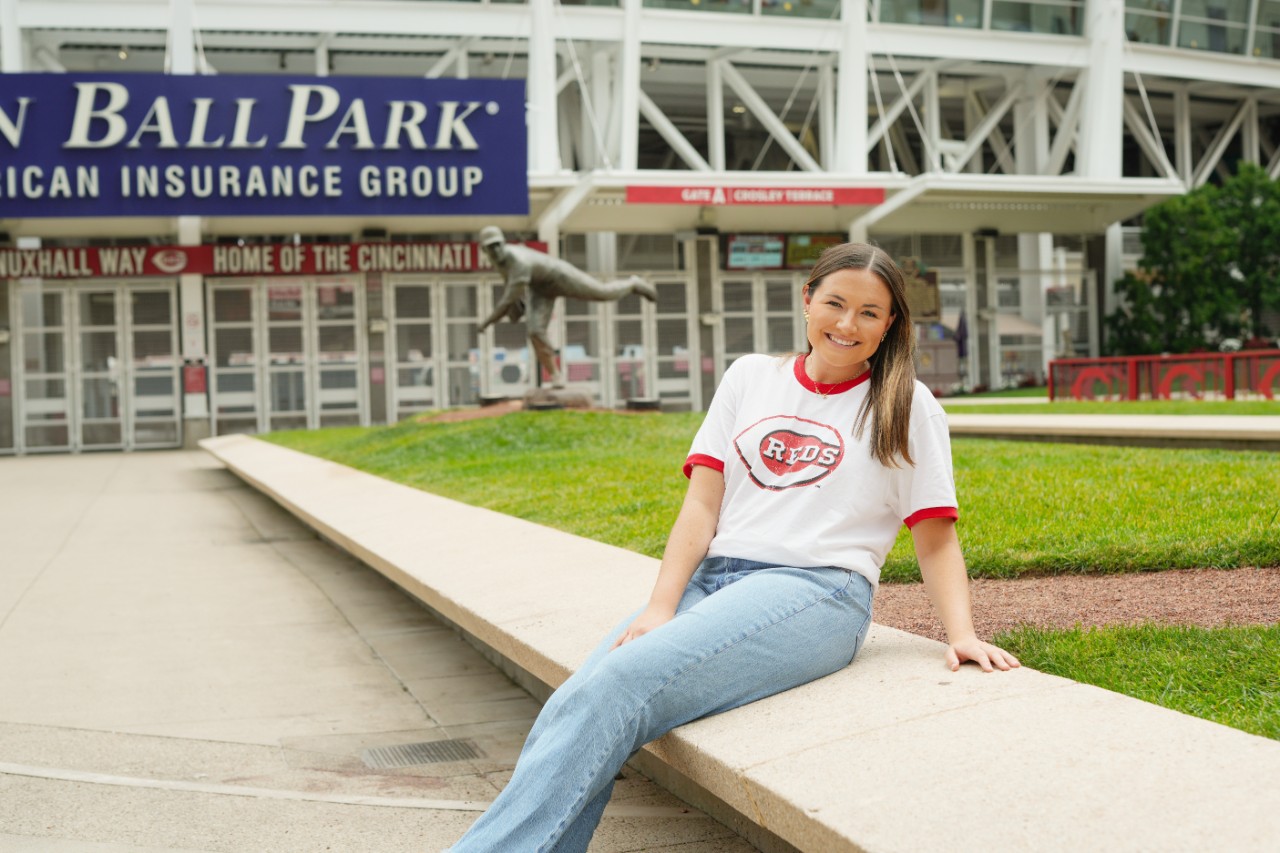 A woman sits with a Cincinnati Reds shirt in front of Great American Ball Park