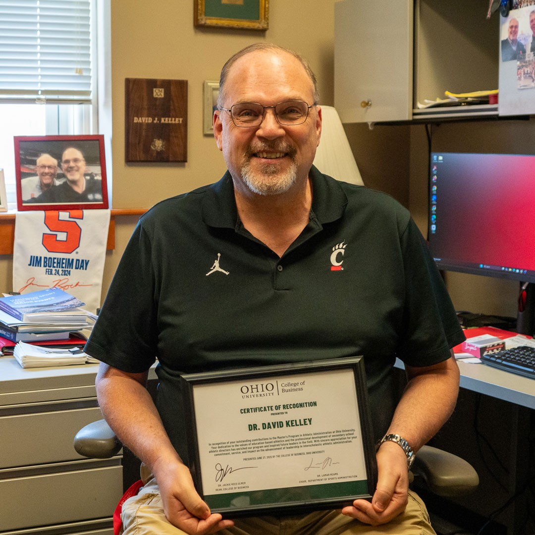 two men stand as one is presented with a certificate