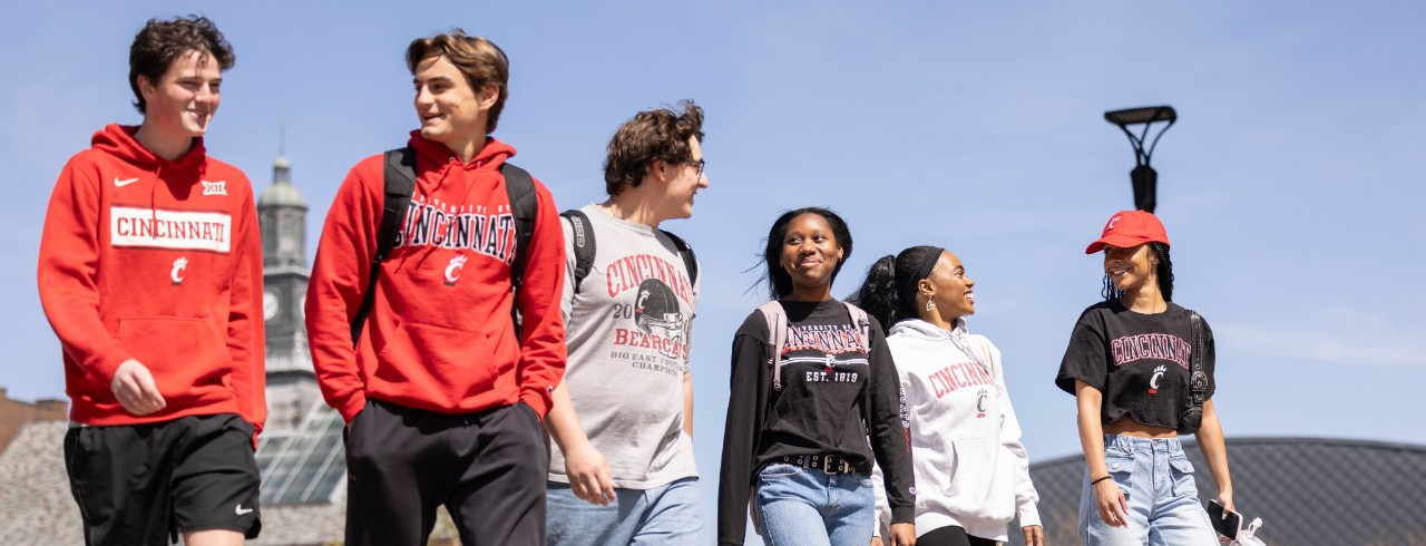 Six students on campus wearing UC shirts.