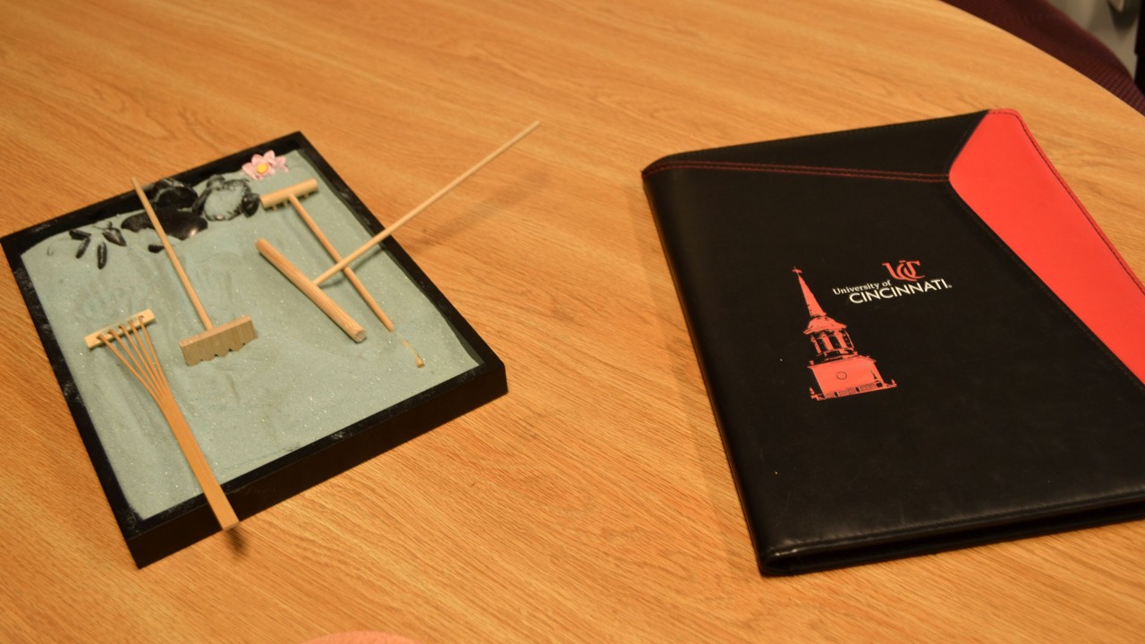 Zen garden sits beside UC handbook on wood grain desk