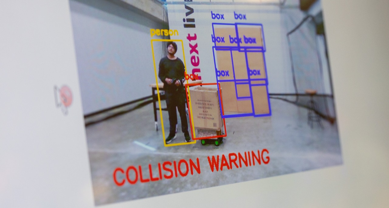 A screen shows a worker with the caption collision warning.
