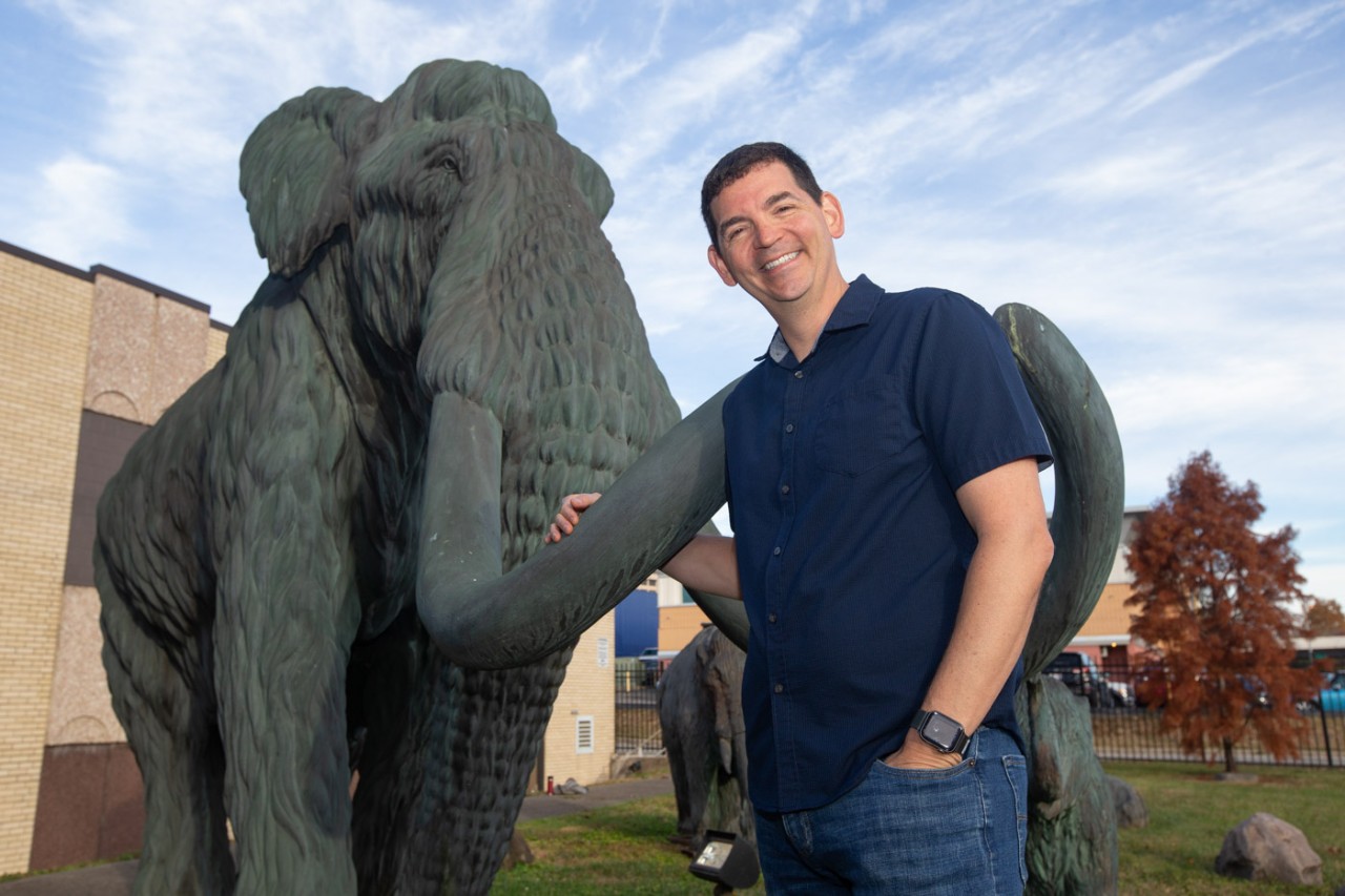 UC assistant professor Joshua Miller with mammoth display and artifacts at the Cincinnati Museum Center's Geier Collections and Research Center