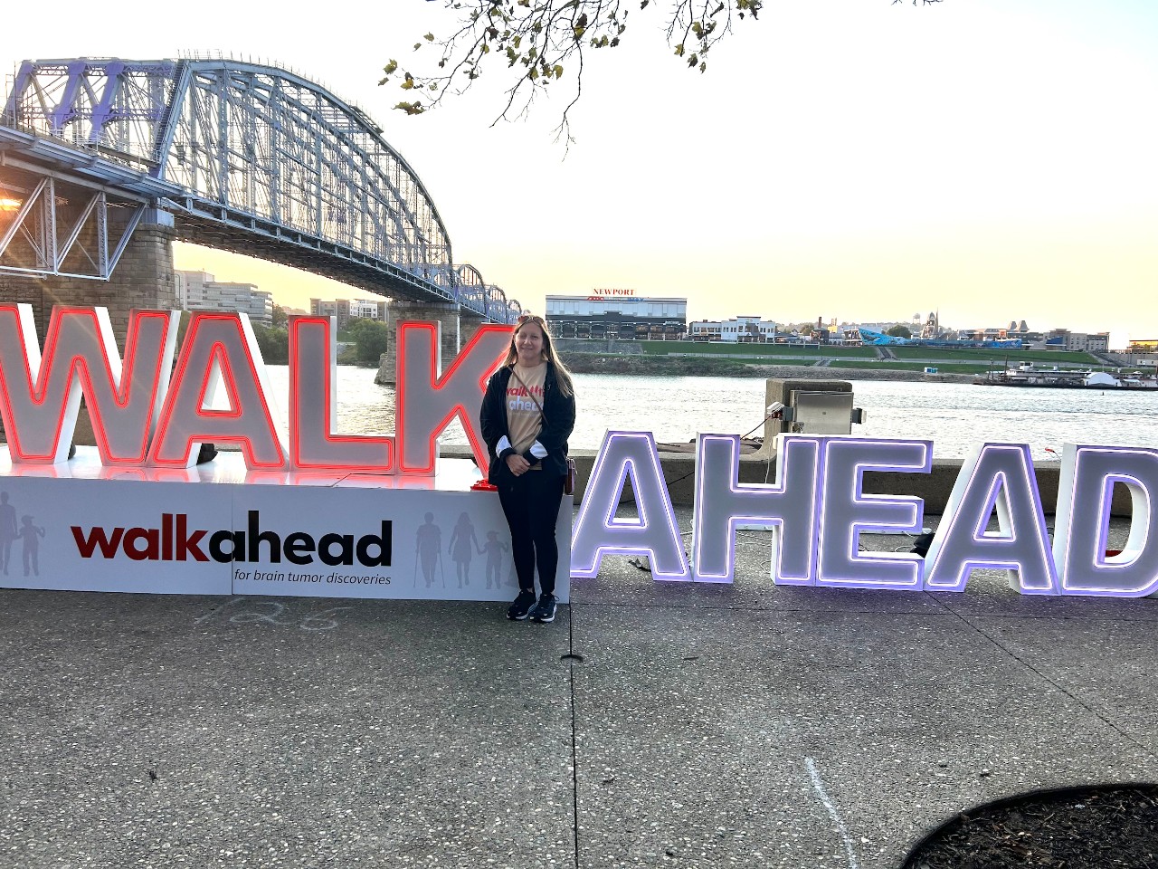 A woman stands in front of the Walk Ahead sign on Cincinnati's Sawyer Point.