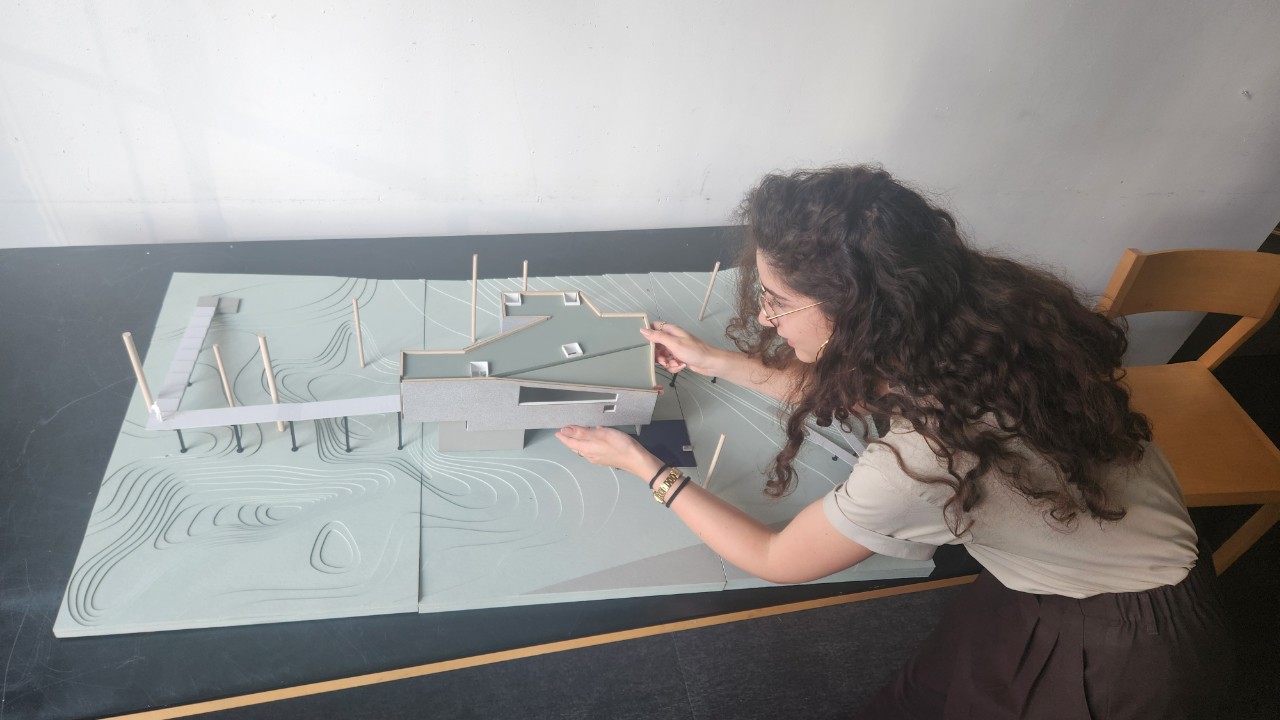 Tamara Nasr at the design table with an architetural model.