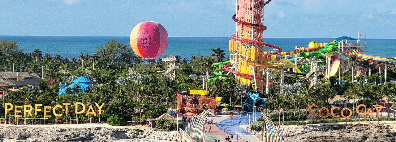 View of Royal Caribbean's Perfect Day at CocoCay private island featuring a large waterpark, helium balloon ride, and a pier extending into the clear turquoise sea.