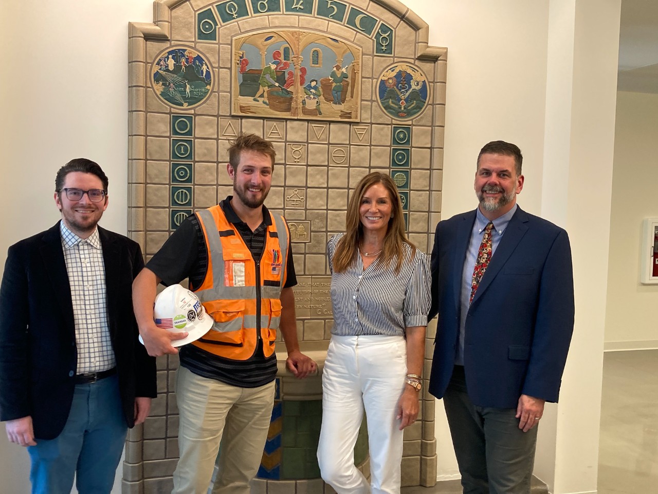 Four people pose for a photo in front of a historic Rookwood fountain.