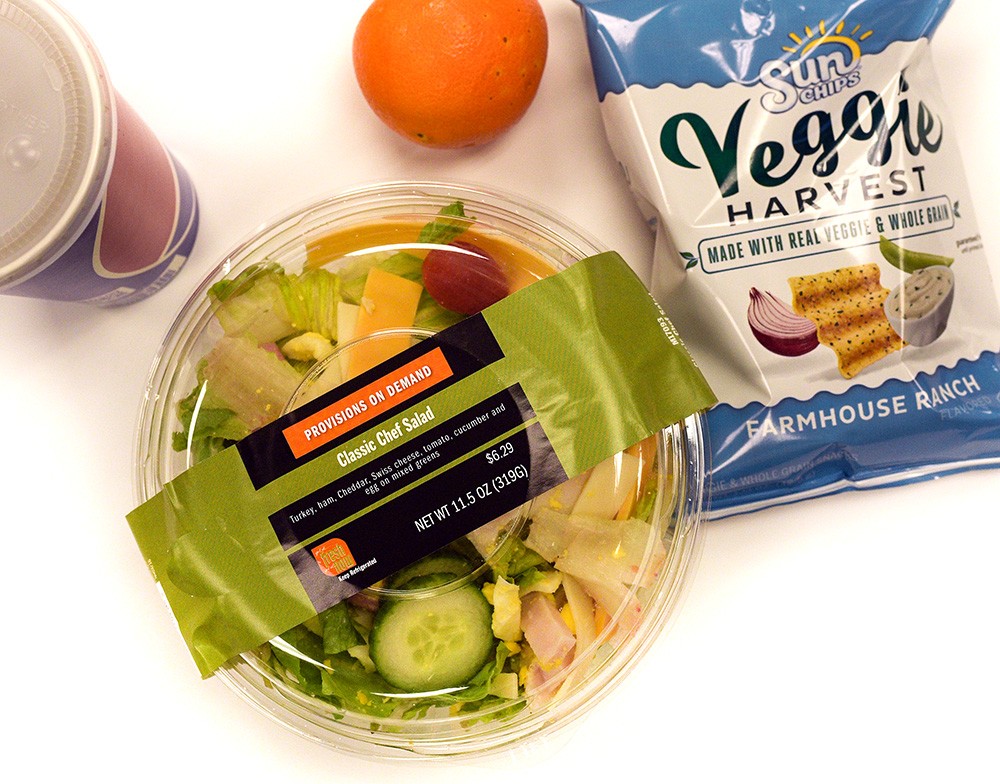An image of chips, orange, a salad, a healthy option for a college grocery list