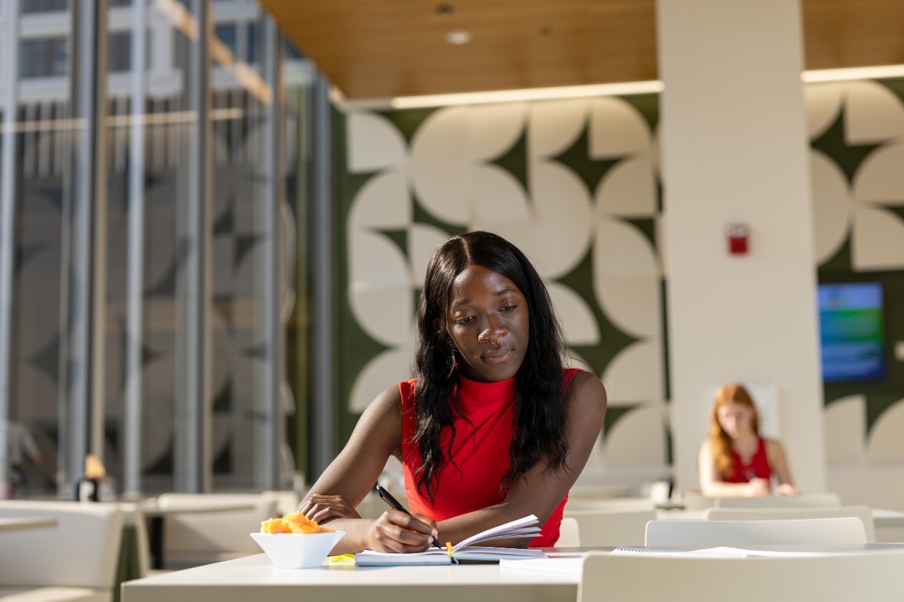 Student taking notes at table while building a college resume