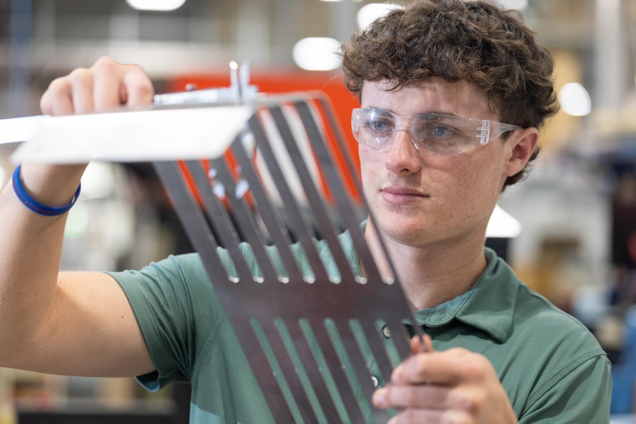 Student holding piece of metal at his internship or co-op