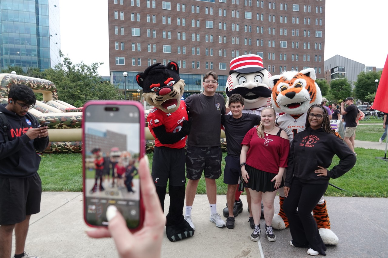 Five students pose with the Bearcats mascot, Bengals mascot and Cincinnati Red mascot on Sigma Sigma Commons