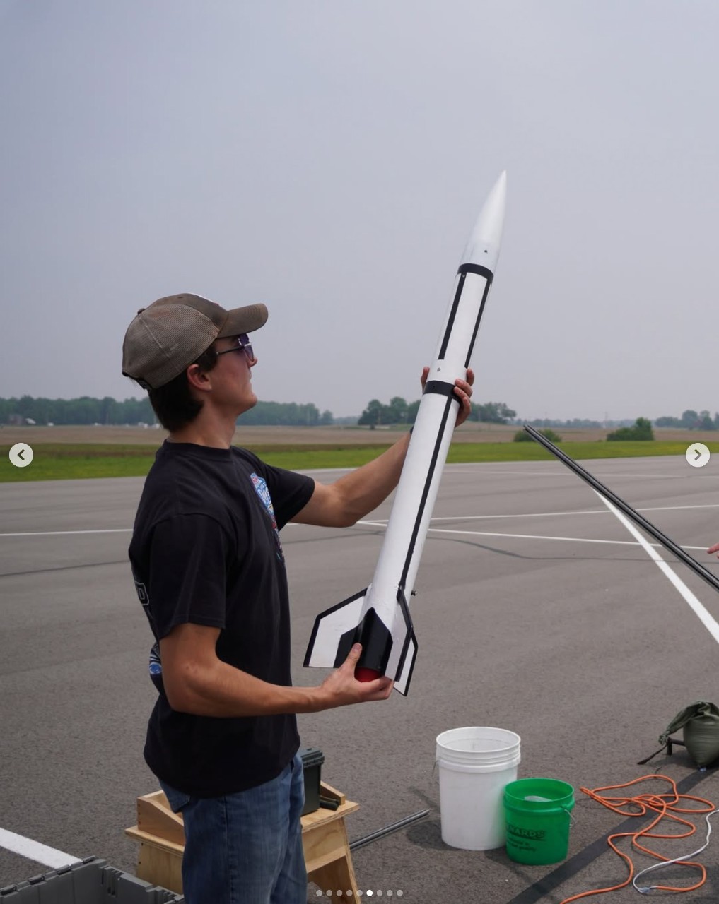 A UC student holds a rocket at an air field.