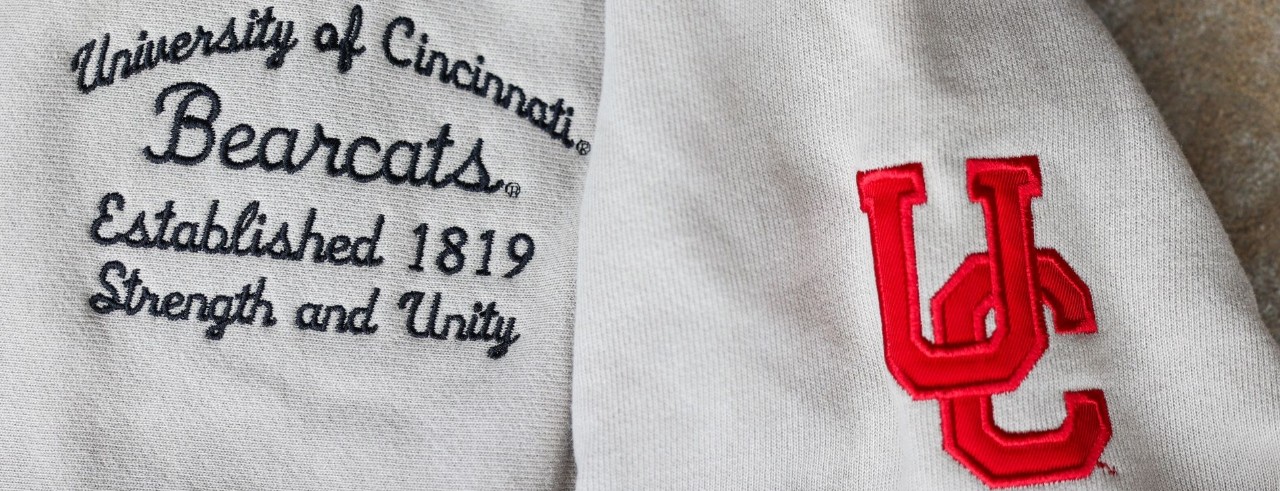 University of Cincinnati written in script on a beige hoodie