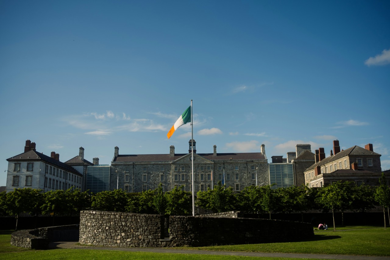Flag of Ireland flies in front of buildings. 