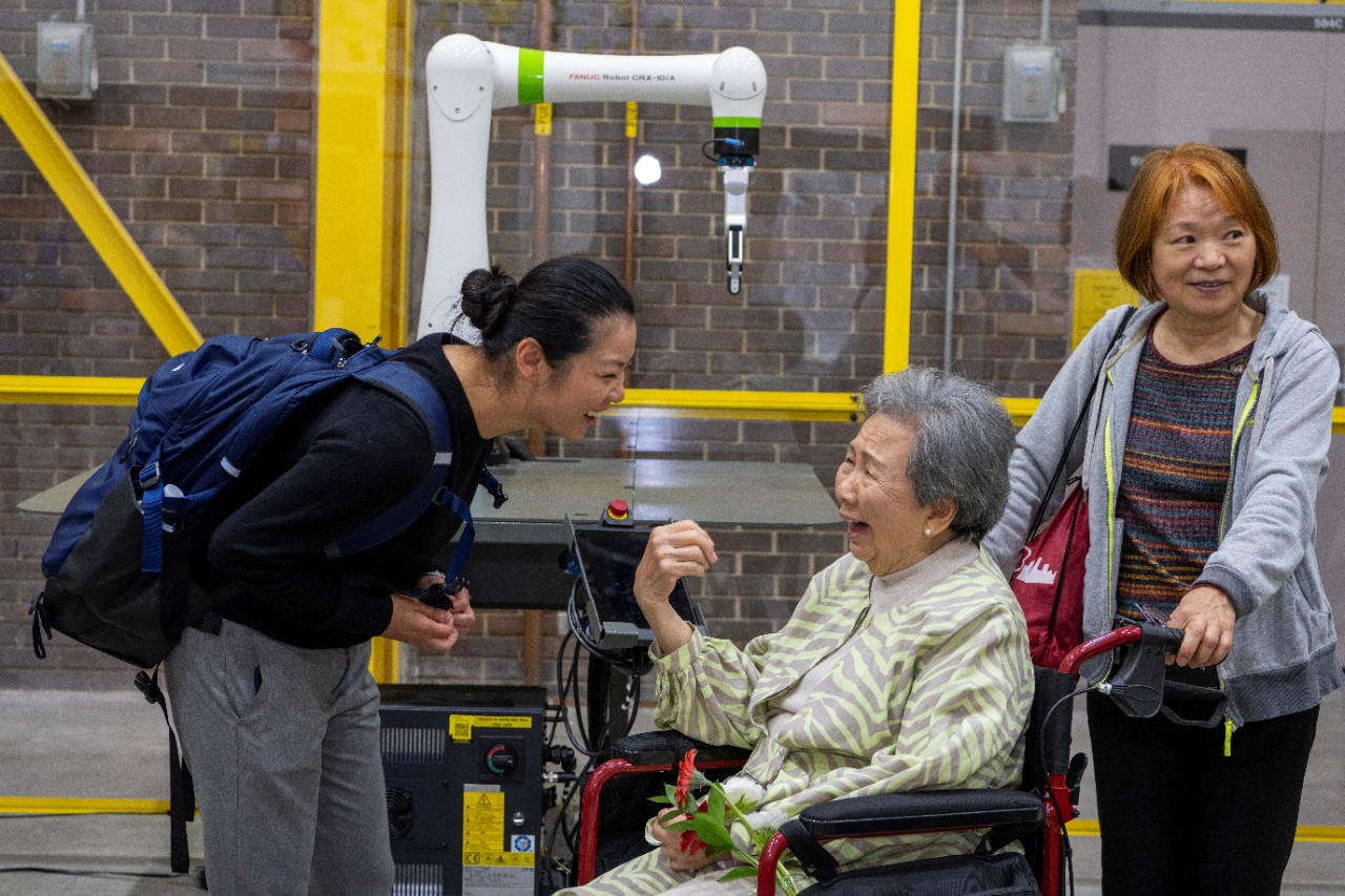 Three people smiling. One in a wheelchair.