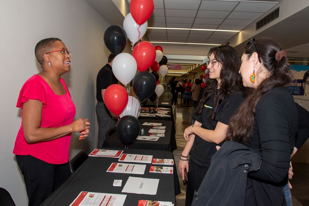 Professor talking with students at open house event