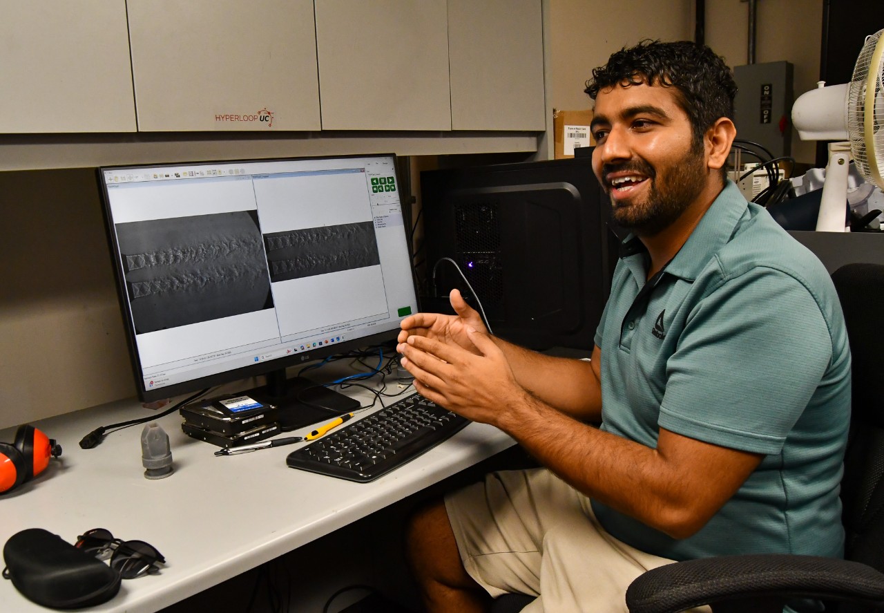 Kaurab Gautam talks in front of a computer screen displaying two examples of air flow from a jet.