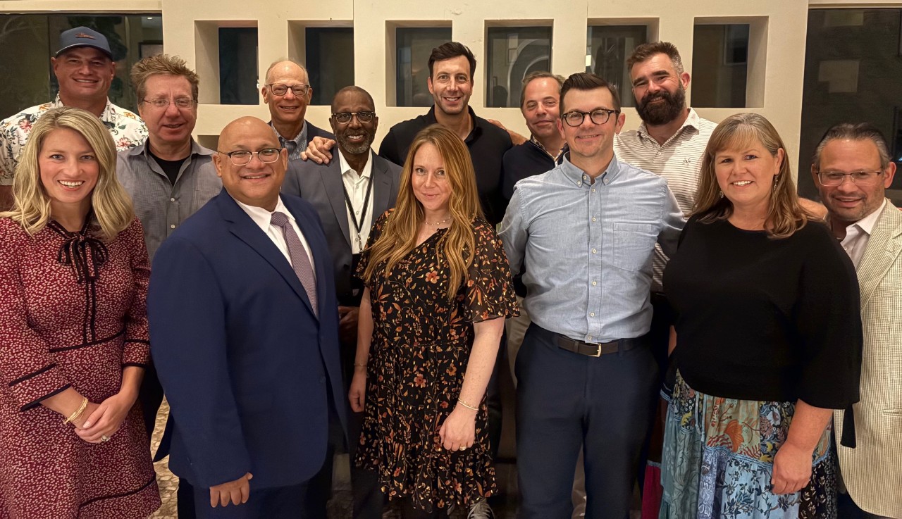 A group of people in a mix of professional dress pose for a picture.