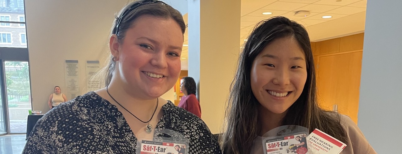 two students holding audiology equipment